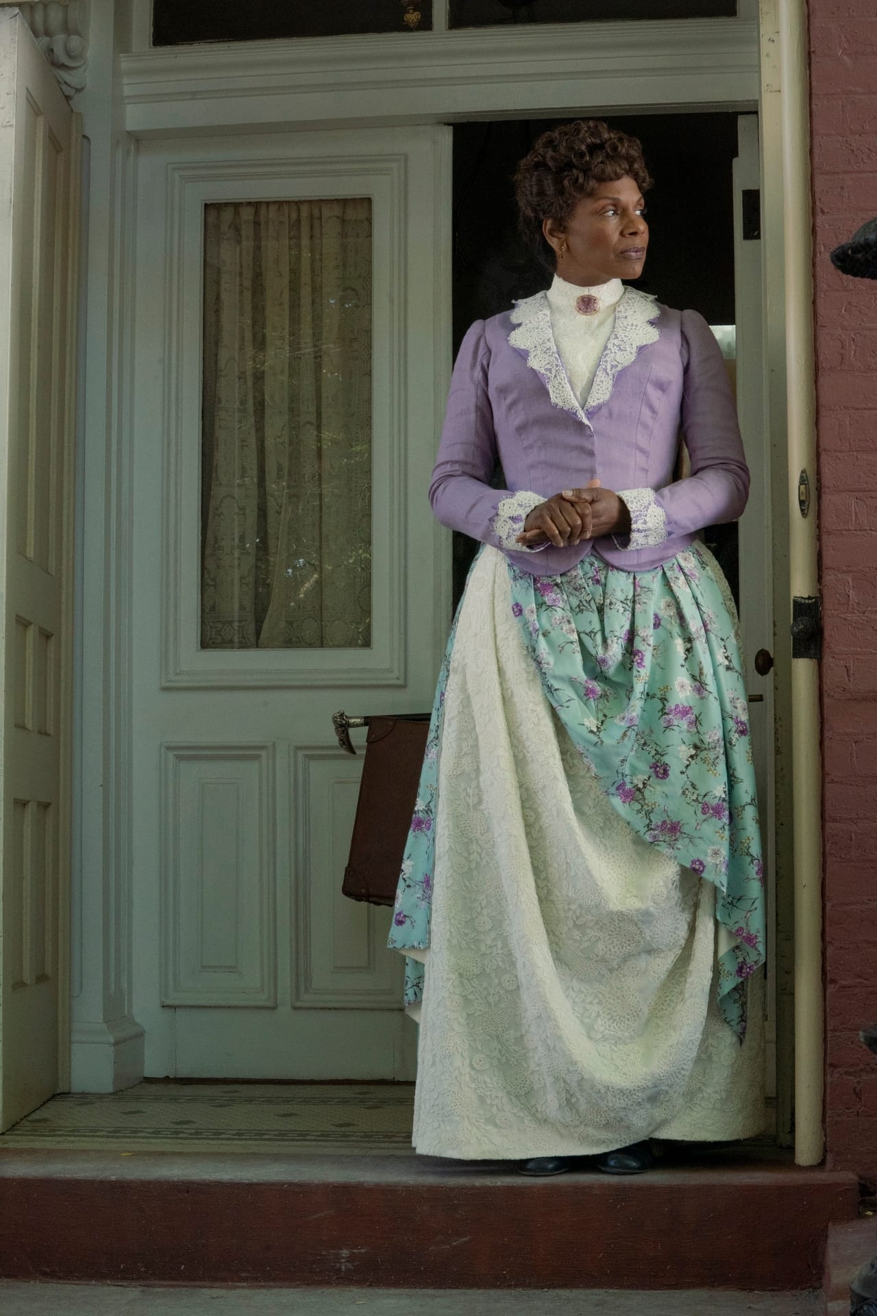 Audra McDonald stands outside a brick house on the set of The Gilded Age