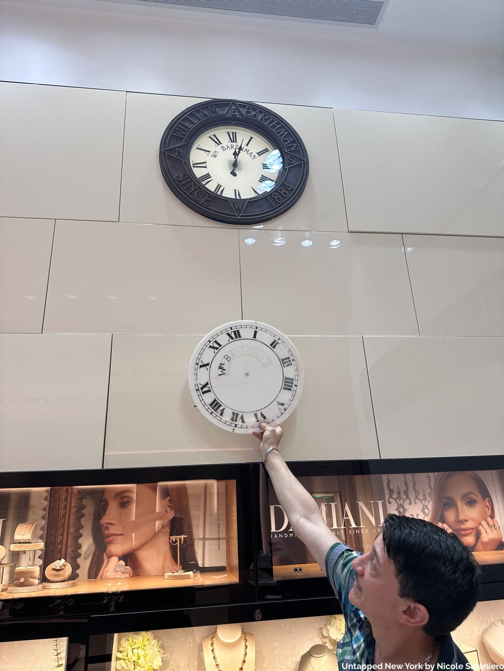Guilo holds an old sidewalk clock face up to the replica at the Broad Street store