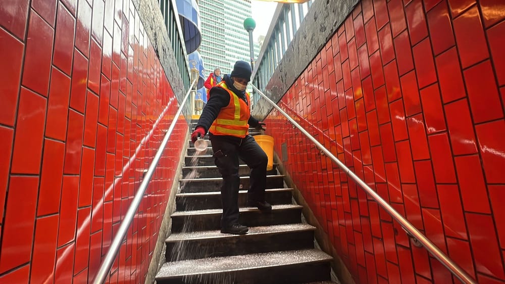 MTA employees spread salt on subway station stairs