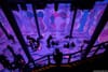 Silhouettes of people sitting inside ARTECHOUSE NYC as abstract purple digital images cover the walls and floor