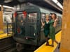 Two women standing on a subway platform next to the NYC Holiday Nostalgia Train