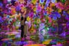 Two women stand amongst digital flowers at Artechouse NYC