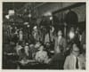 Dinners sit at tables inside Gage & Tollner as a staff member lights the gas fixtures overhead