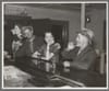Black and white photo of two men and two women drinking at a bar