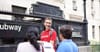 A tour guide addresses two guests at a subway entrance